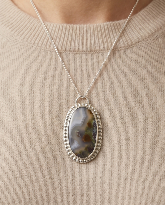 Oval scenic agate pendant with natural landscape pattern set in sterling silver.
