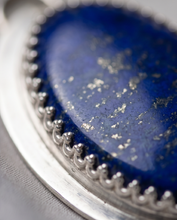 Load image into Gallery viewer, Oval Lapis Lazuli pendant set in handcrafted sterling silver with decorative bezel detailing.
