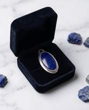 Load image into Gallery viewer, Oval Lapis Lazuli pendant set in handcrafted sterling silver with decorative bezel detailing.
