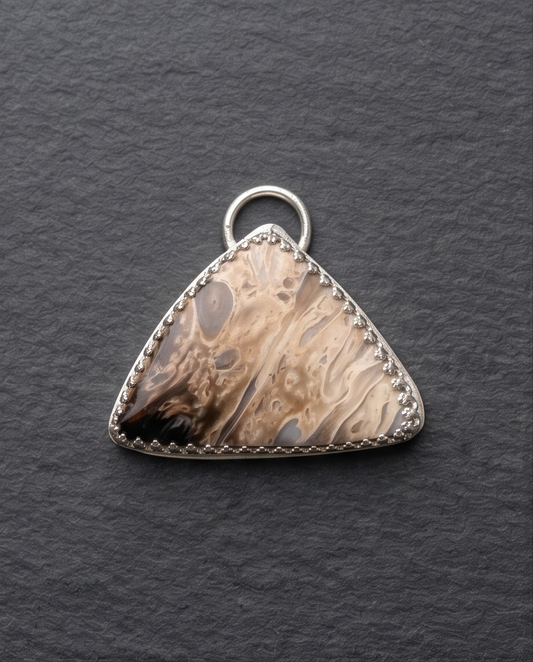 Lifestyle image of Model wearing a handcrafted Palm Root pendant in sterling silver on a delicate chain and crafted in sterling silver.  Palm Root pendant featuring natural fossil patterns and earth-tone petrified wood markings
