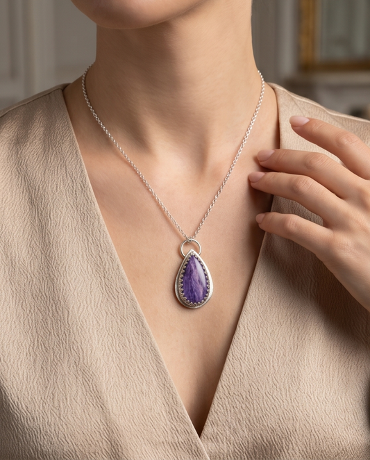 Lifestyle image of handcrafted sterling silver Charoite teardrop pendant featuring natural lavender and violet gemstone patterns
