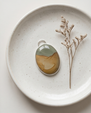 Load image into Gallery viewer, Lifestyle image of handcrafted sterling silver Picture Jasper pendant featuring natural tan, cream, and gray earth-tone patterns