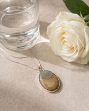 Load image into Gallery viewer, Lifestyle image of handcrafted sterling silver Picture Jasper pendant featuring natural tan, cream, and gray earth-tone patterns
